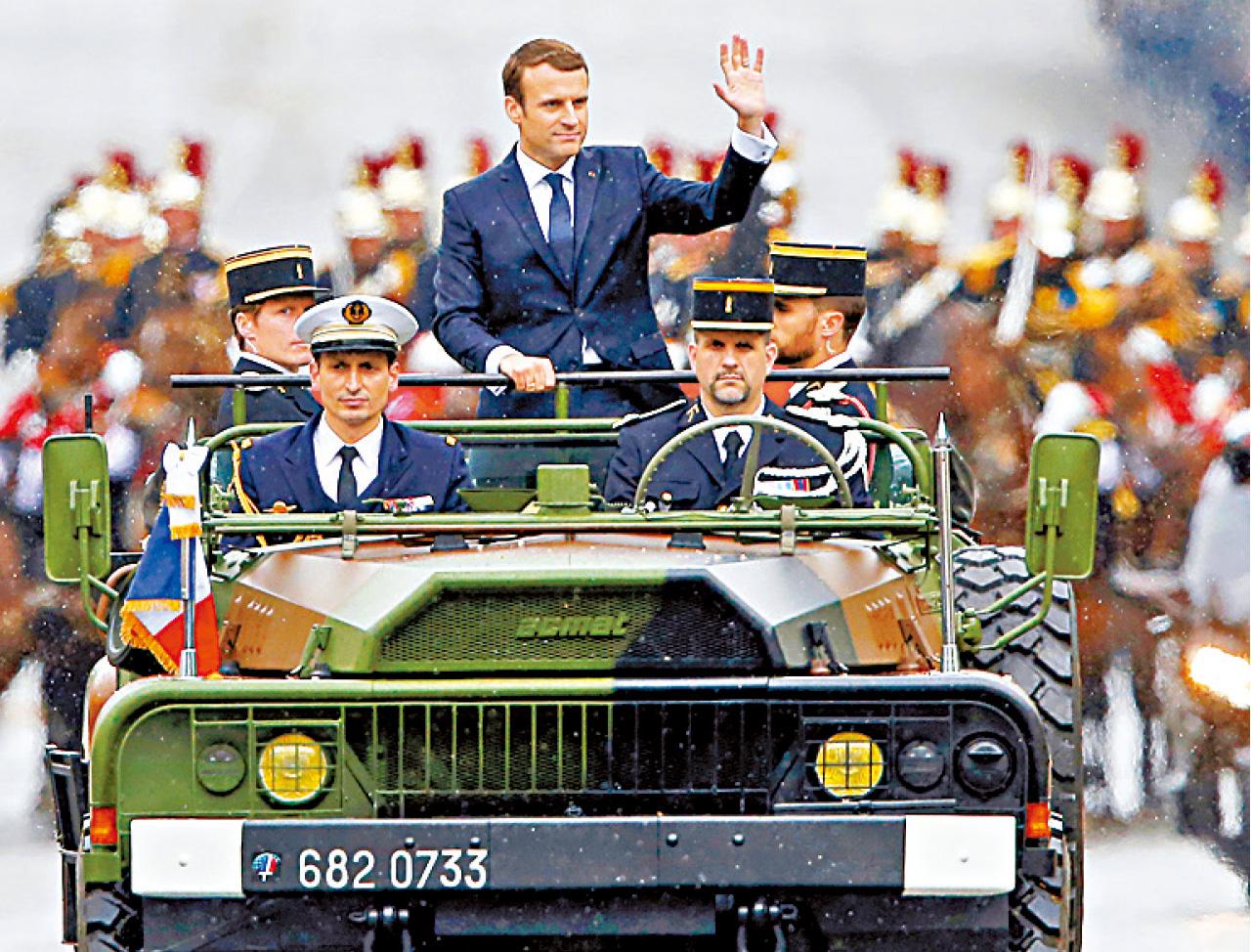 馬克龍乘開蓬車往無名士兵墳墓獻花,途中向民眾揮手。(路透社)