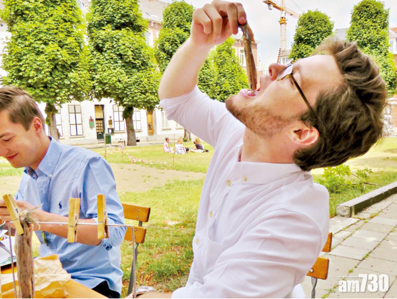 大專廣場上學生示範用荷蘭傳統方法吃鯡魚。