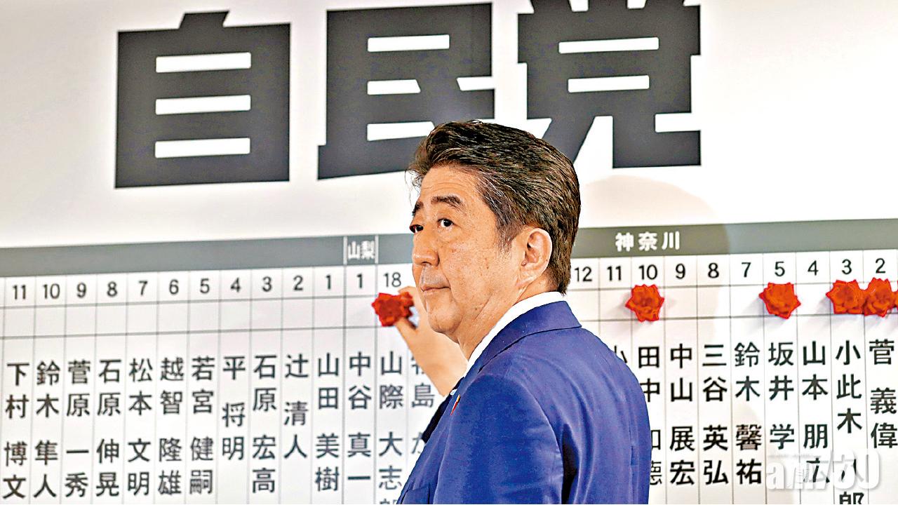 安倍為當選的自民黨候選人貼上紅花。