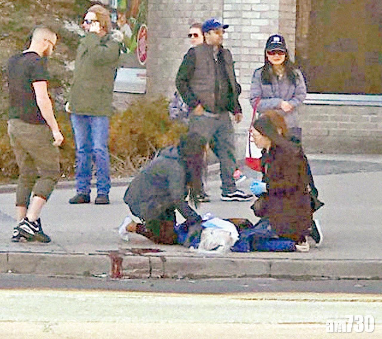 途人照顧一名等待救援的傷者。