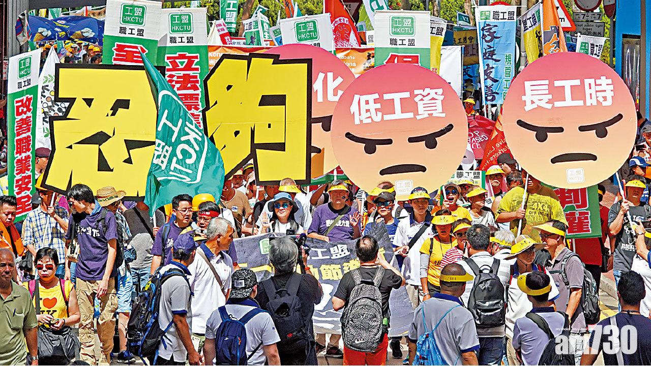 遊行人士高舉「忍夠」、「低工資」、「長工時」等紙牌,要求政府制定標準工時。(陳奕釗攝)