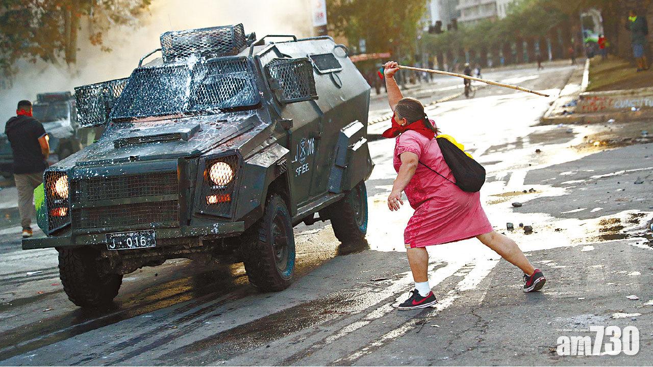 智利反政府示威持續,令當局被迫取消主辦峰會。圖為一名婦人周三在聖地牙哥追打警車。(路透社)