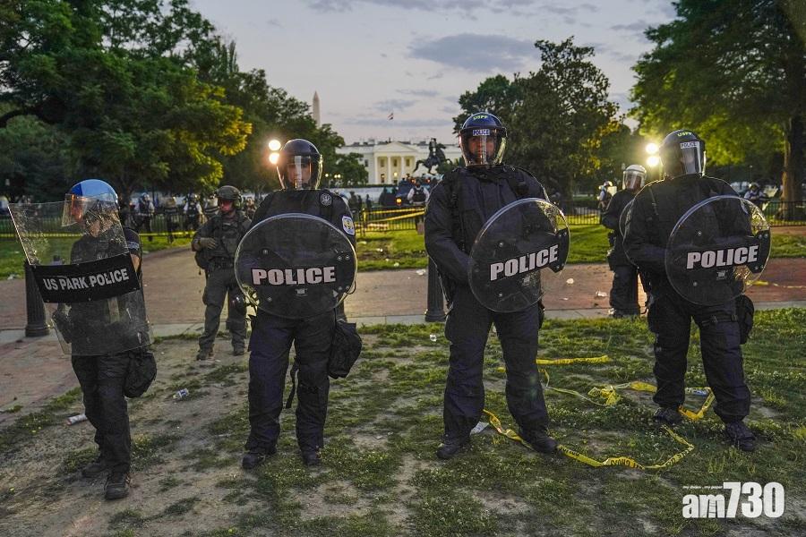 防暴警察站在白宮前,阻止示威者闖入。(美聯社)