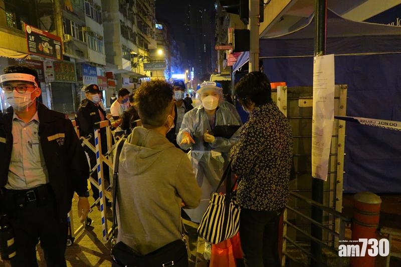 身穿防護衣的人員在受限局域入口查詢及登記入內的市民。(鍾式明攝)