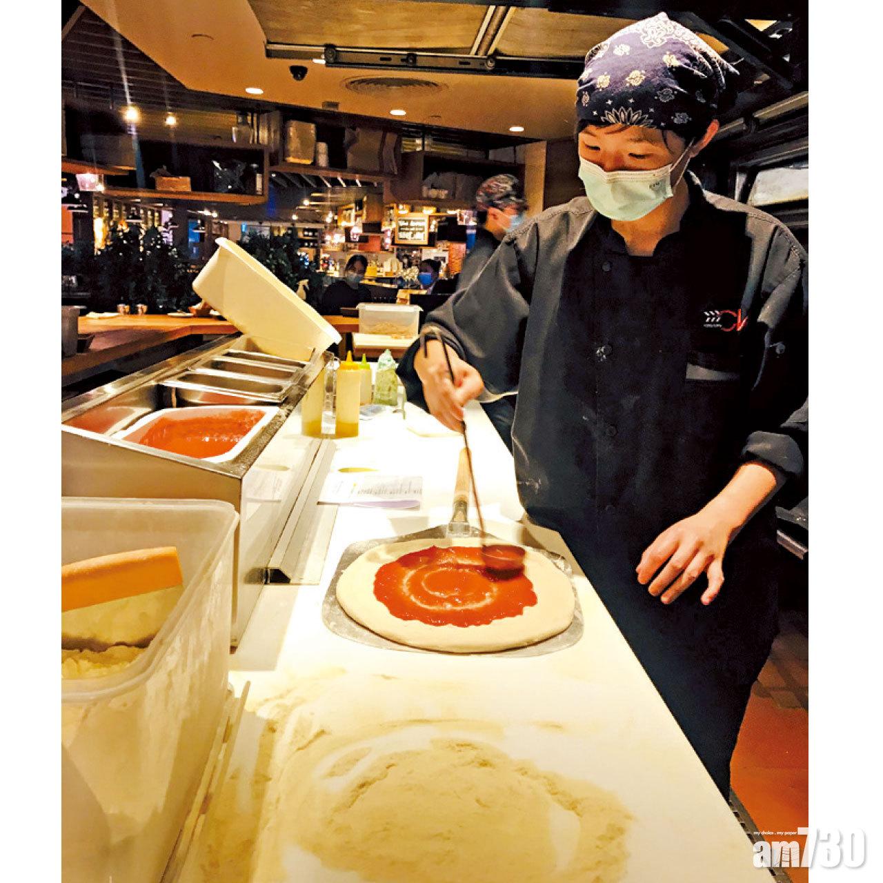 廚師準備於薄餅底鋪上材料。