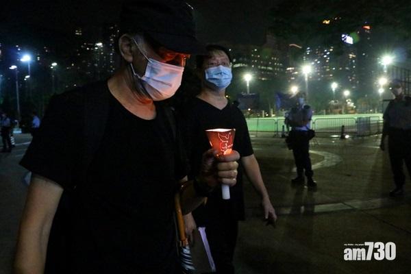 大批警員在維園外把風,有身穿黑衣、手持燭光的男子走過。(林俊源攝)