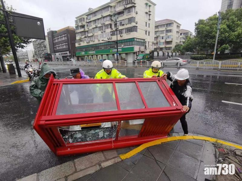 上海有公共電話亭被強風吹倒,警方和附近民眾合力將其推回行人路。(互聯網)