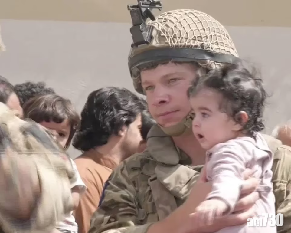 英軍抱著一名從圍牆接過的嬰兒。(互聯網)