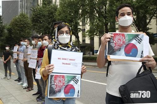 居南韓的阿富汗人周一在外交部外舉起標語,要求當局拯救在阿富汗替南韓工作的親人。(美聯社)