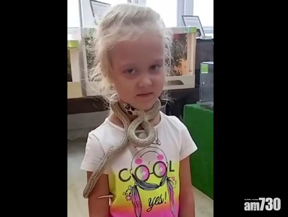 女童讓蛇纏頸拍照,顯得有些惶恐不安。(互聯網)