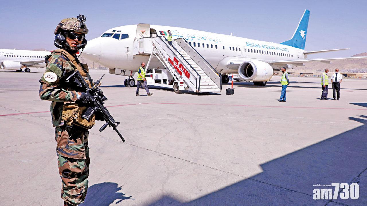 一架客機周日從坎大哈飛抵喀布爾,塔利班部隊在場看守。(路透社)