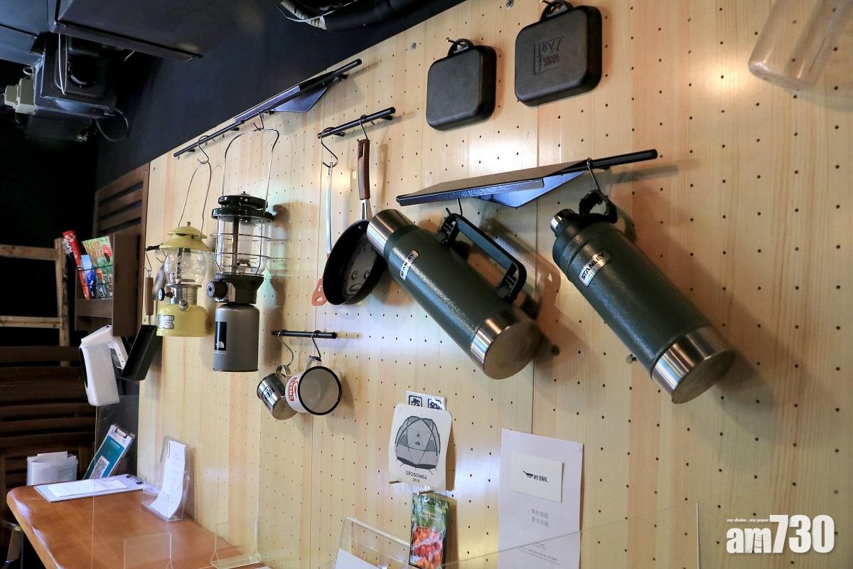 老闆用露營燈和野炊用具等布置牆身。