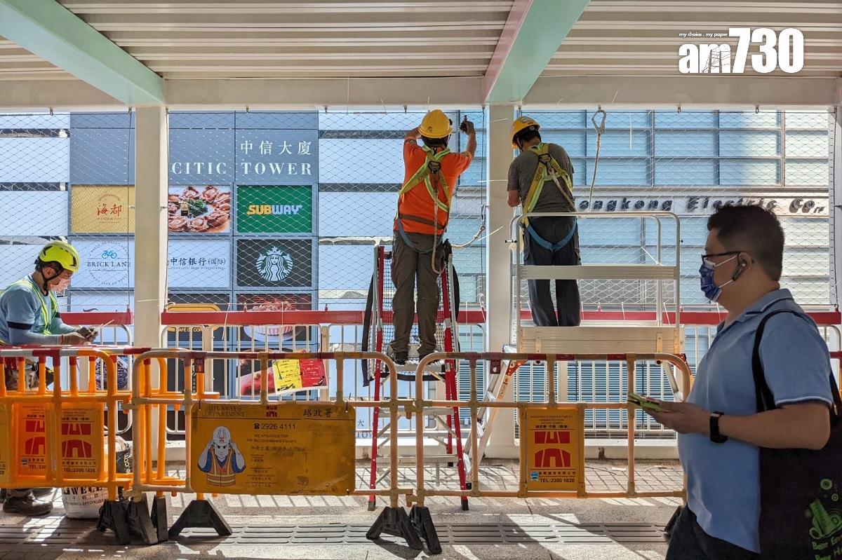 橫跨金鐘夏慤道、連接政府總部的行人天橋,有工人正安裝較輕型及耐用的圍網。(羅庸軒攝)