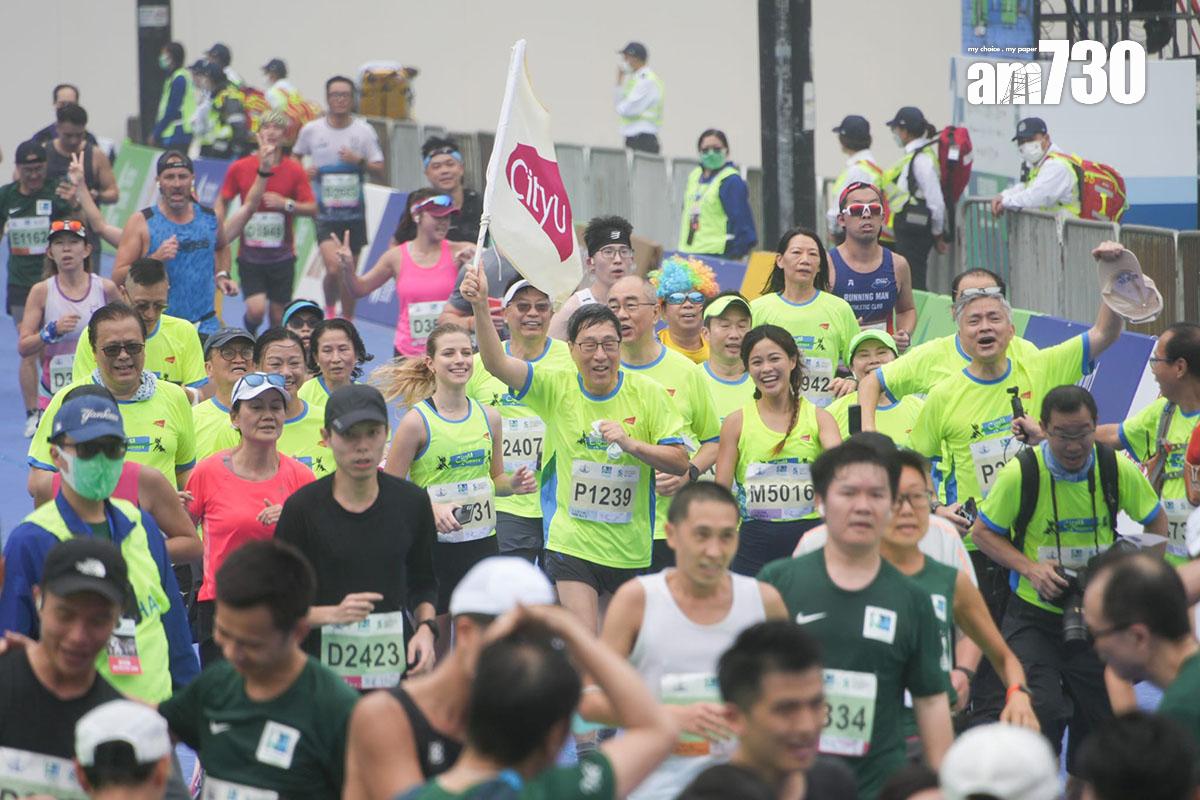 渣打馬拉松2月12日舉行,跑手陸續抵達設於銅鑼灣維多利亞公園的終點,包括香港城市大學校長郭位(持旗者)。(李睿哲攝)