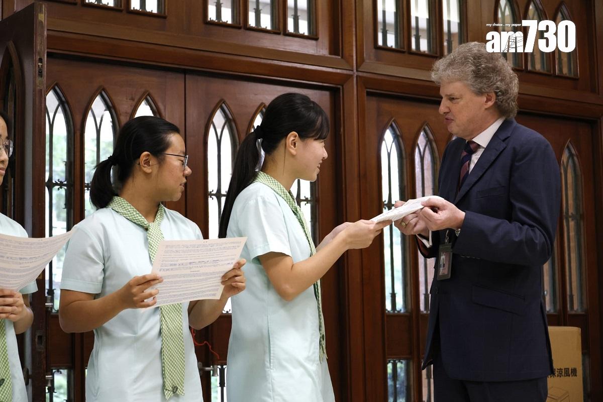 德望學校狀元鄭苡晴(中)從校長(右)手上接過DSE成績單。(林俊源攝)