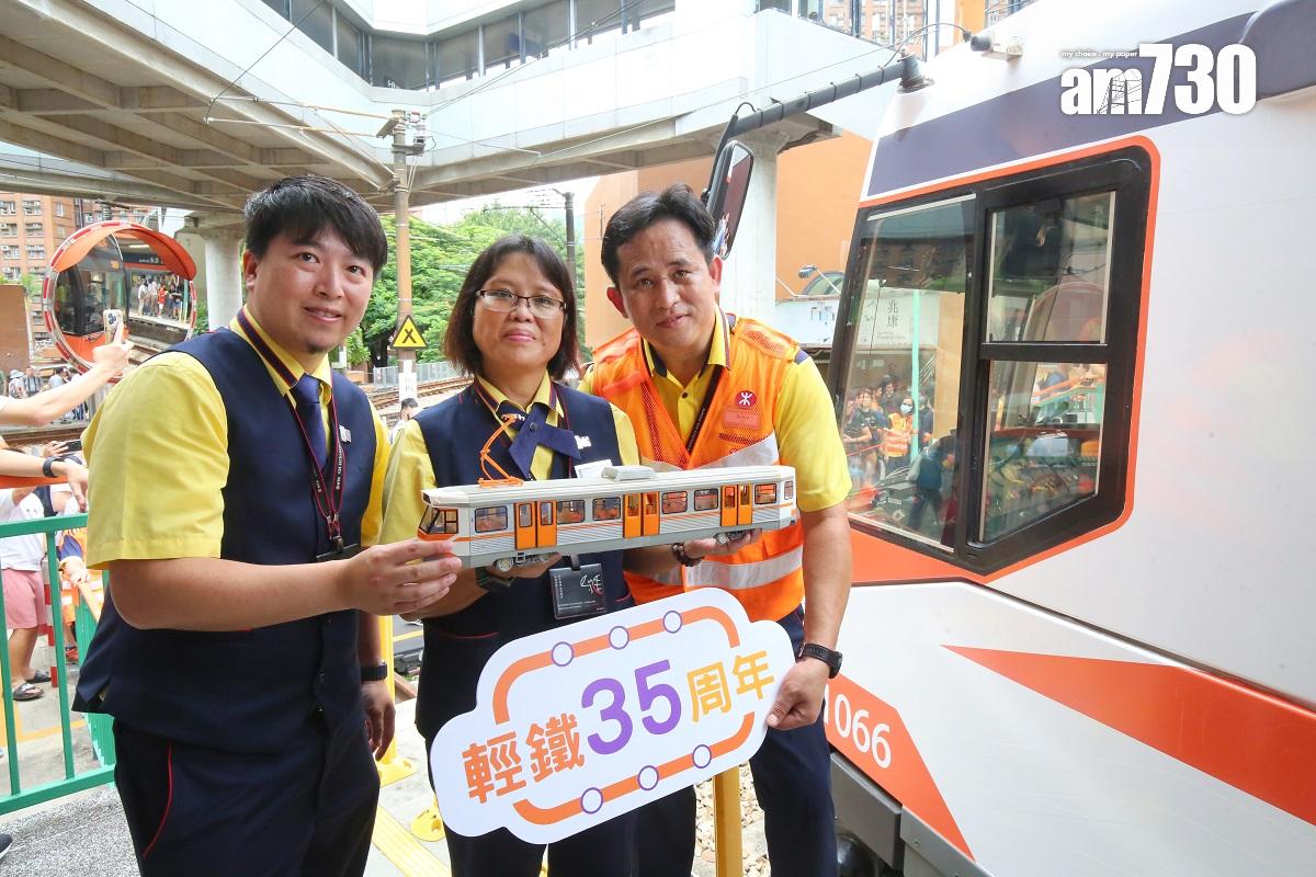 港鐵員工在「35周年復刻主題輕鐵」前,手持初代輕鐵模型合照。(董立華攝)