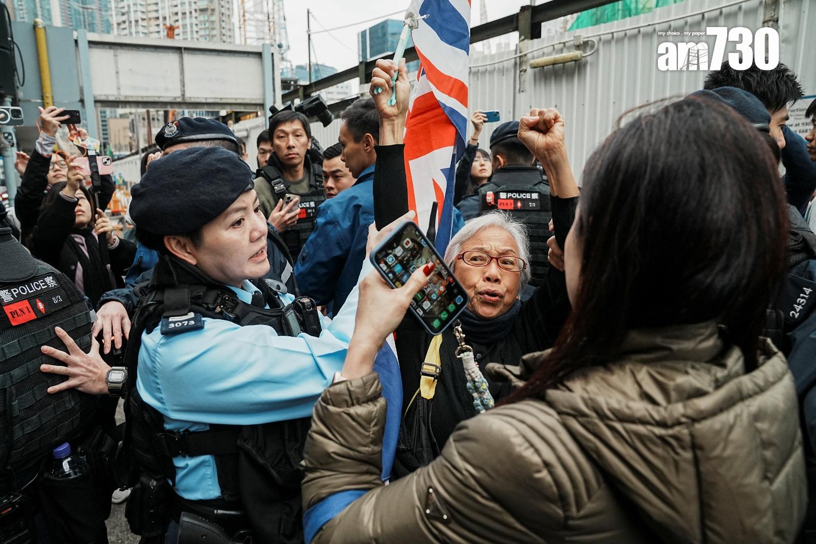 「王婆婆」在庭外揮旗示威,遭警員帶到對面行人路。(路透社)