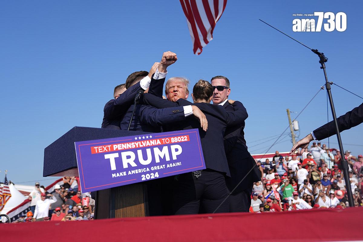 特朗普遇刺後由大批特工護送離開,其間他不忘高舉雙手示意不認輸。(美聯社)