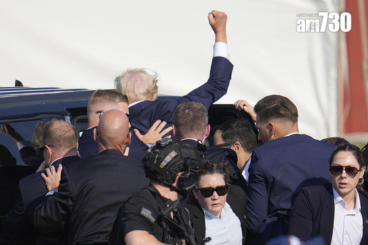 特朗普遇刺後由大批特工護送離開,其間他不忘高舉雙手示意不認輸。(美聯社)