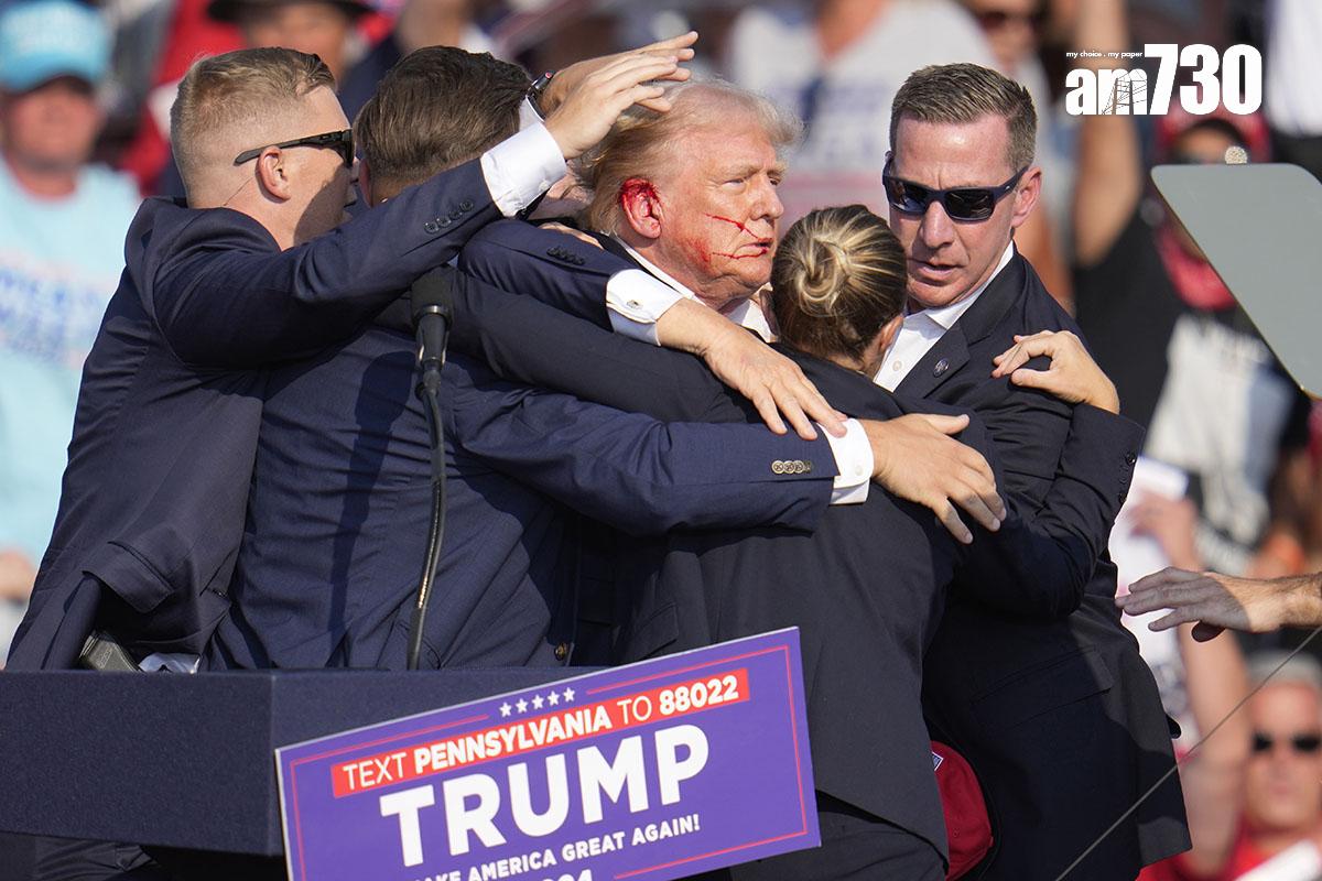 特朗普遇刺後由大批特工護送離開,可見他右耳流血。(美聯社)