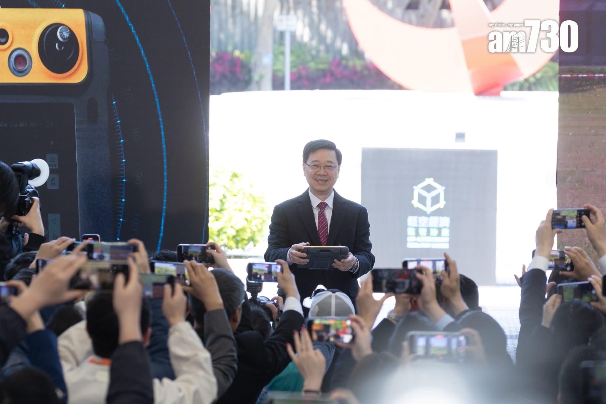 主禮的李家超在典禮上,用遙控器操控無人機,運送色彩繽紛的膠球到會場。(蘇文傑攝)