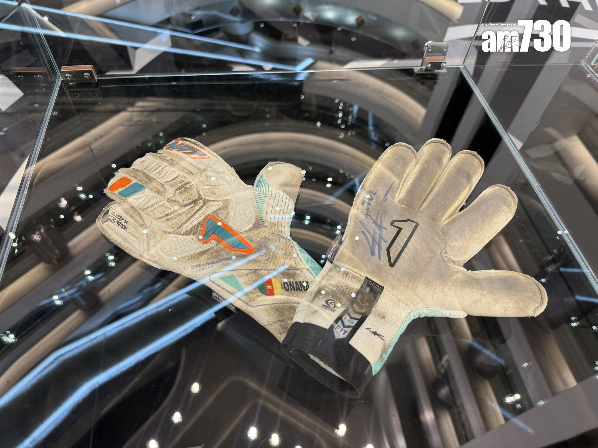 奧拿拿(Onana)使用過的門將手套,可見明顯使用痕跡與草地污漬,手背印有代表號 碼「1」與國旗標誌,手掌處並附有親筆簽名。(本報攝)