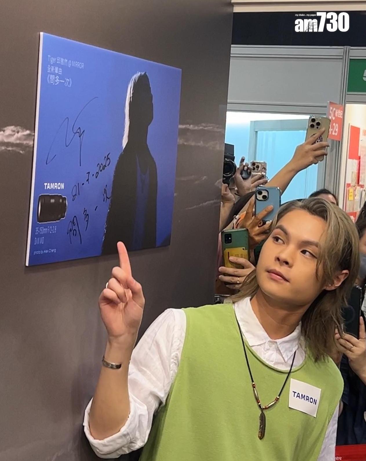 邱傲然Tiger@MIRROR即席在MV攝影展的作品上簽名留念。(娛樂組攝)