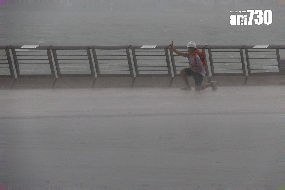 韋帕襲港期間,尖沙咀有人在海邊感受風力。(蘇文傑攝)