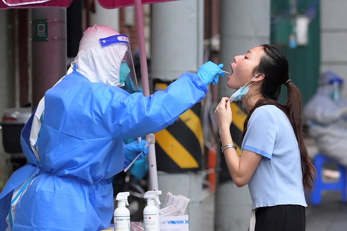 廣東省和四川省昨錄得18宗來自香港的輸入個案。圖為內地民眾接受檢測時被醫護人員採樣。(美聯社)