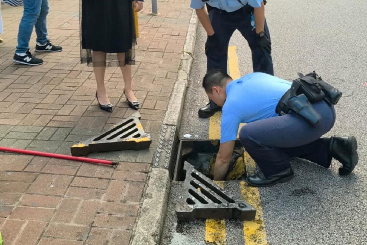 旺角有警員協助內地遊客從坑渠扣拾回財物。(旺角警區FB)