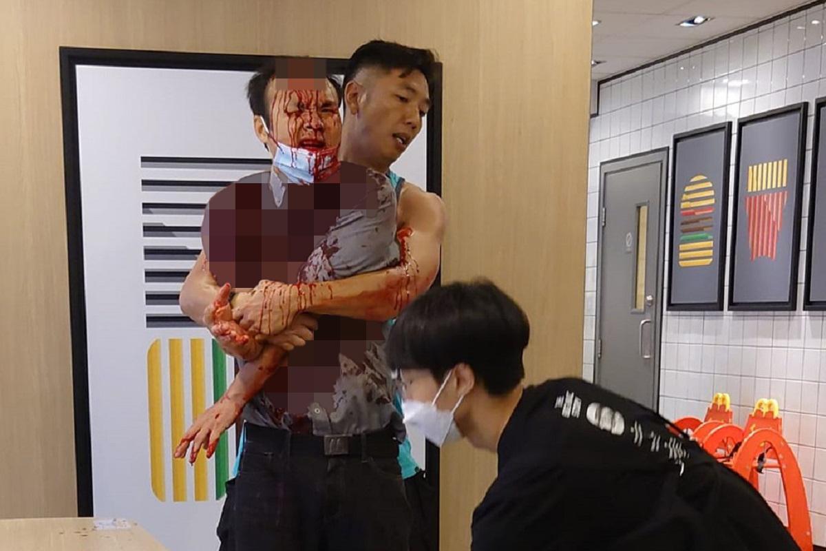 一名身穿背心的男子昨日扶抱浴血經理，據悉他是一名休班消防總隊目。(網民Alexander Wong圖片)