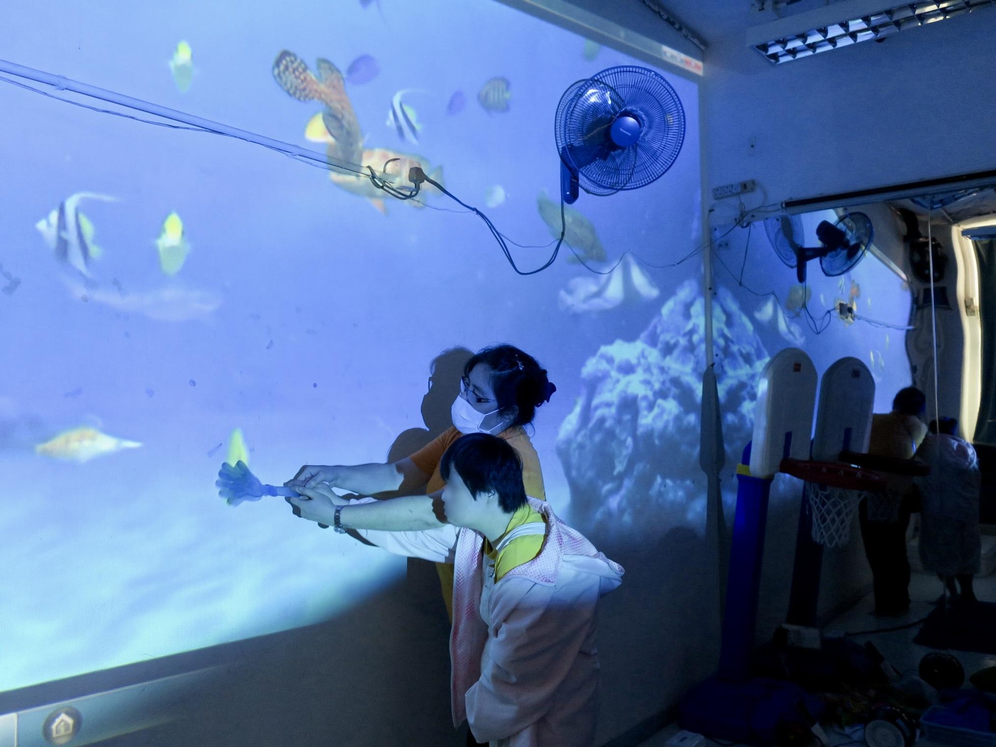 學員在光影投射下進行海底探索康樂活動，刺激他們的感官之餘，亦讓他們的院舍生活增添樂趣。