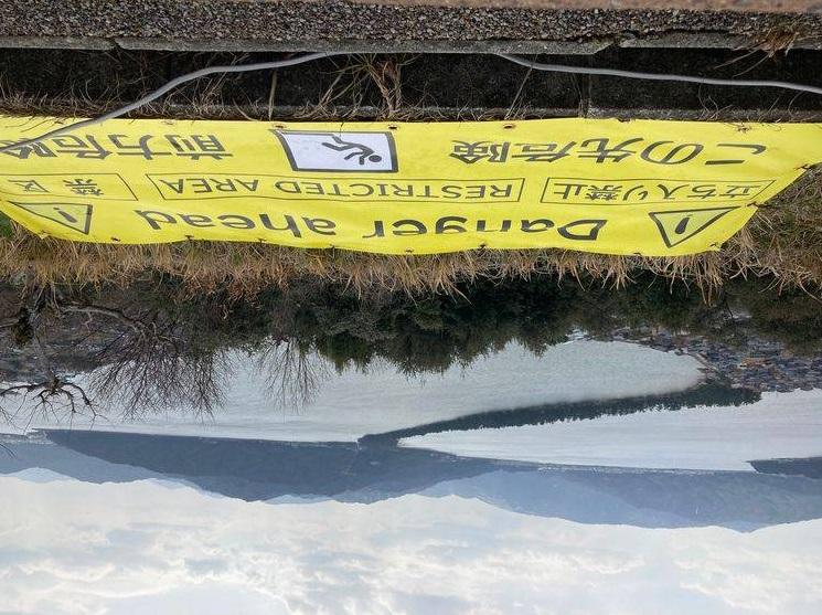 網民拍下加了巨型警告橫額的「胯下觀景」的天橋立景色。(互聯網)