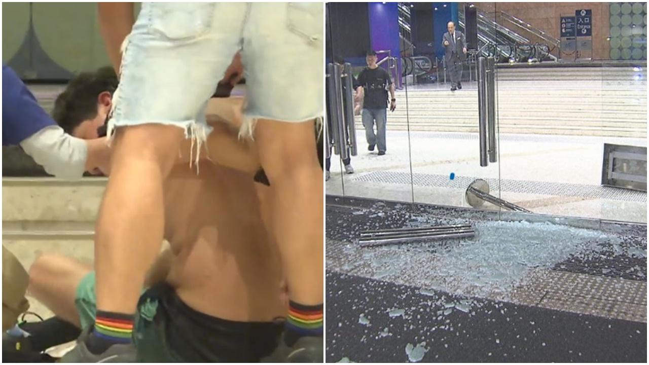 灣仔會展玻璃門遭砸毀，赤膊外籍醉漢由保安和警員制服。(電視截圖)