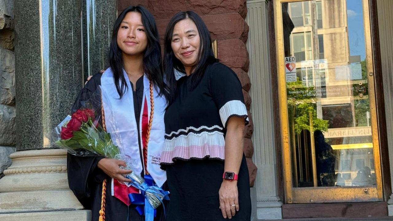 我和披着畢業袍的女兒，在康奈爾大學圖書館門前。(筆者提供)