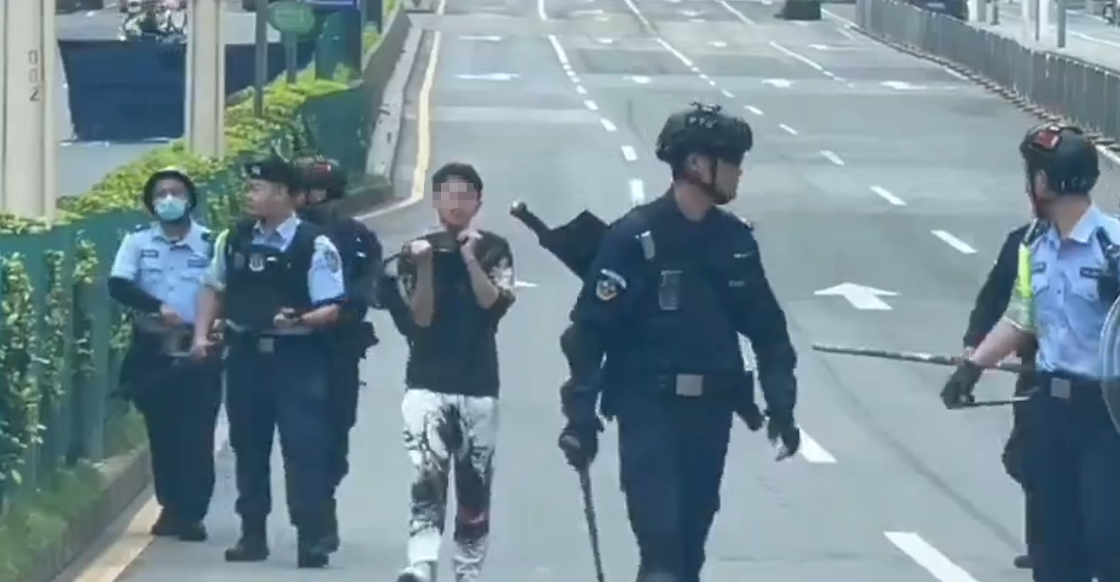 廣東東莞一名涉嫌持菜刀搶劫的男子，在虎門鎮虎門大道路中央手持菜刀架在自己的頸前方，與現場全副武裝的警方對峙，他最終被制服逮捕。(影片截圖)