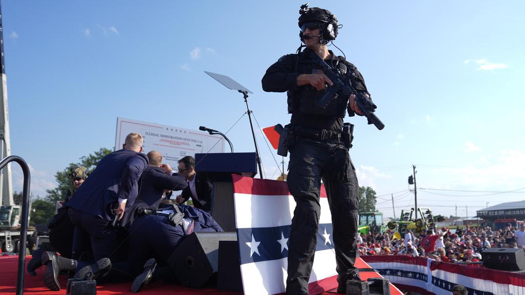 特朗普中槍後伏下，特勤人員衝上台以身體掩護他，特種警察持槍戒備。(資料圖片)