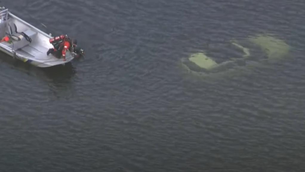 休閒車沉在河中，消防蛙人乘小艇接近。(互聯網)