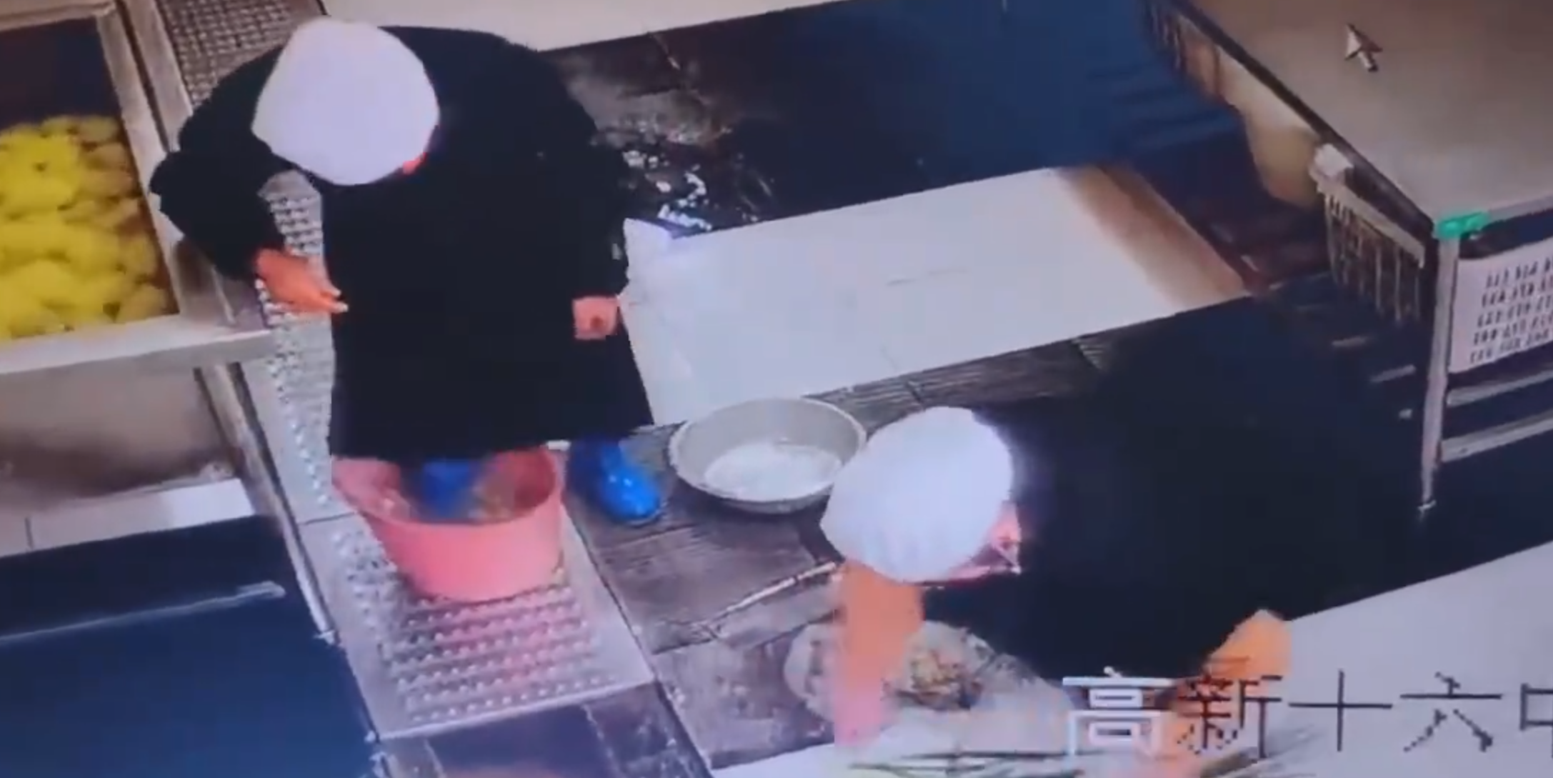 江西新余市第十六中學食堂有一名戴廚師帽的員工用腳多次踩踏水桶內的食材，當時他還穿著水靴。(影片截圖)