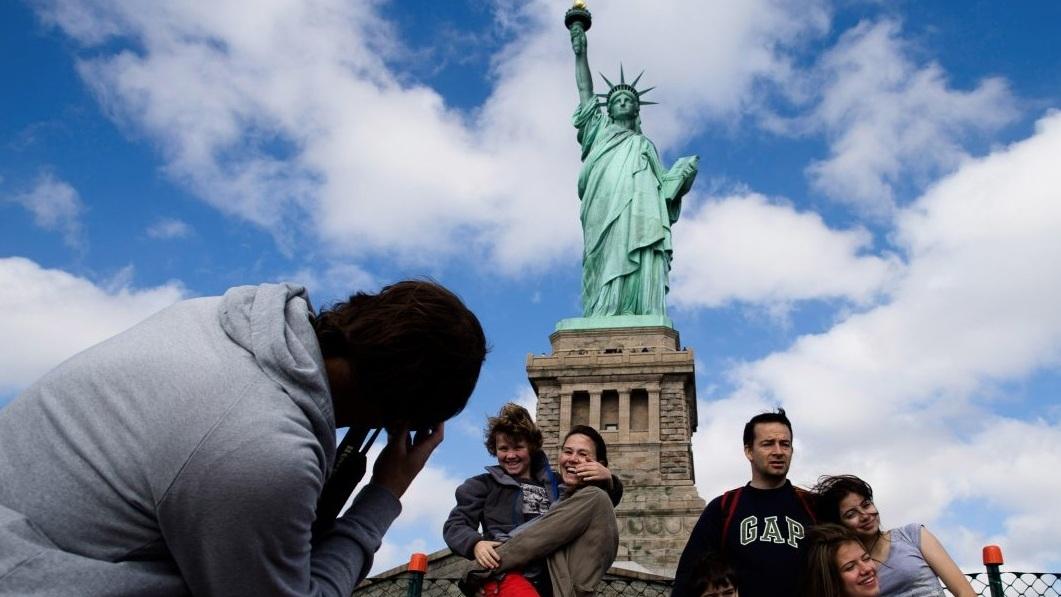 遊客在紐約景點自由神像前打卡。(資料圖片)