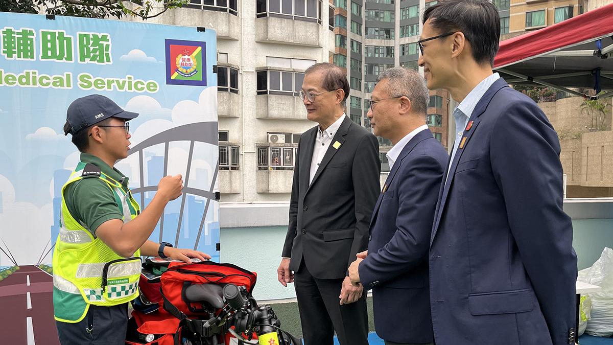 盧寵茂(左二)聽取有關醫療輔助隊急救單車服務的介紹。(政府新聞處)