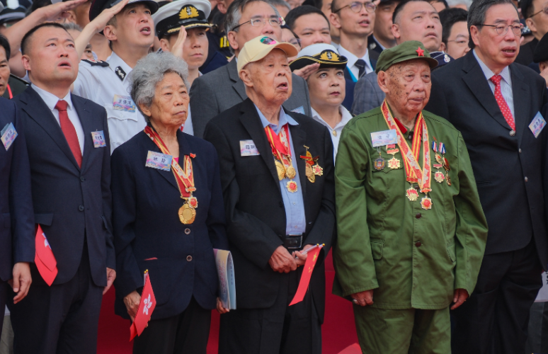 5月4日早晨，為紀念五四運動106周年及中國人民抗日戰爭暨世界反法西斯戰爭勝利80周年，香港各界青少年活動委員會於金紫荊廣場舉行升旗禮。圖為東江縱隊香港地區抗日遊擊隊老戰士林珍（左二）、羅競輝（左三）、梁平（右二）出席升旗禮。（中通社）