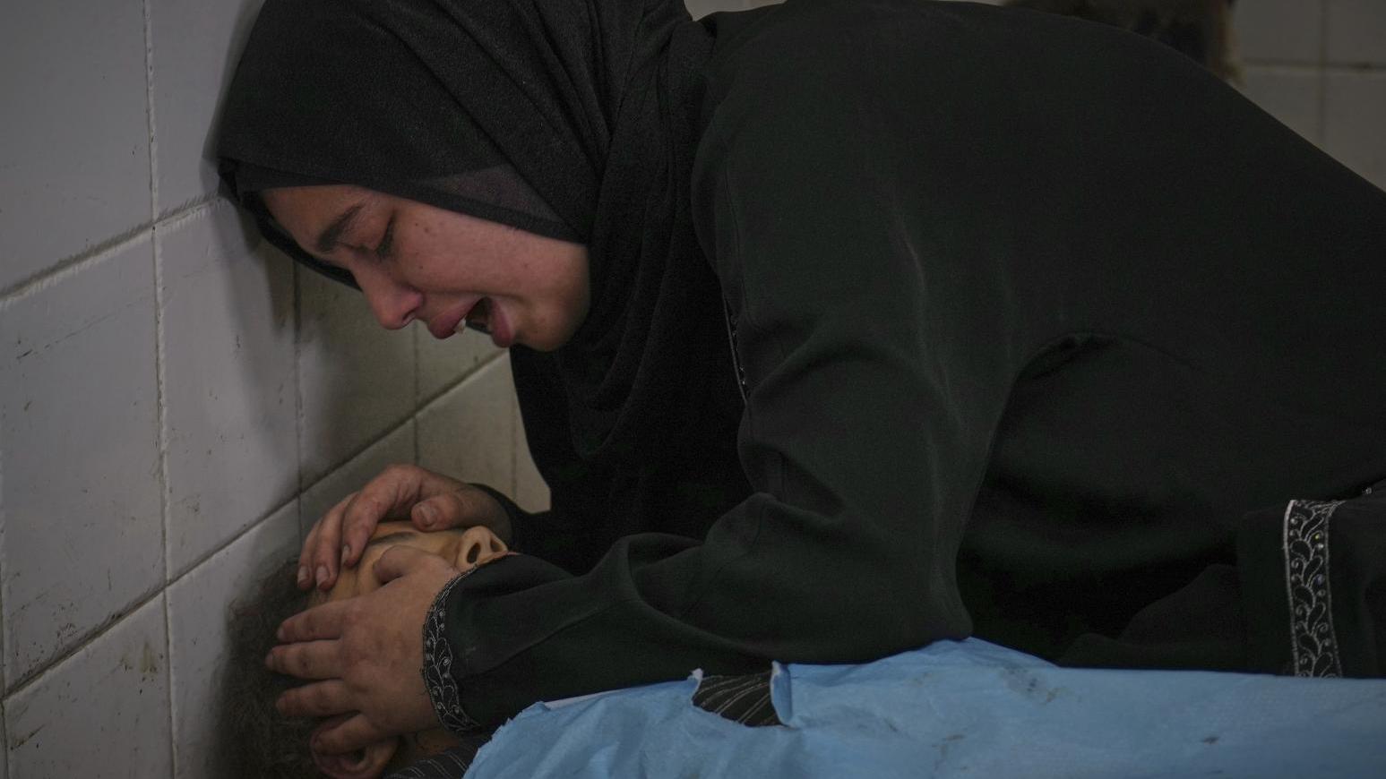 7月10日，一名巴勒斯坦女子在姊妹的遺體旁痛哭。死者薩瑪（Sama）在「希望工程」診所等待領取營養補充劑時命喪以色列襲擊。（圖／美聯社）