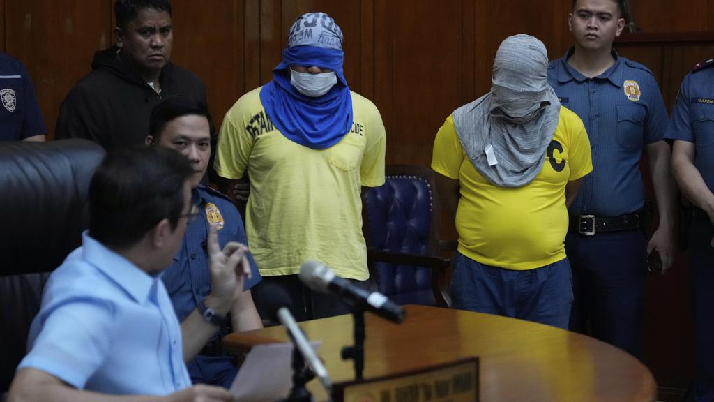 馬尼拉市長周二公布調查進展，兩名被捕疑犯蒙面，被帶到記者會。(美聯社)