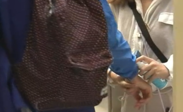 禮賢會恩慈學校今日照常上課，學生進入學校前，有教師為他們噴蚊怕水、塗抹蚊膏和度體溫。(now新聞台畫面)