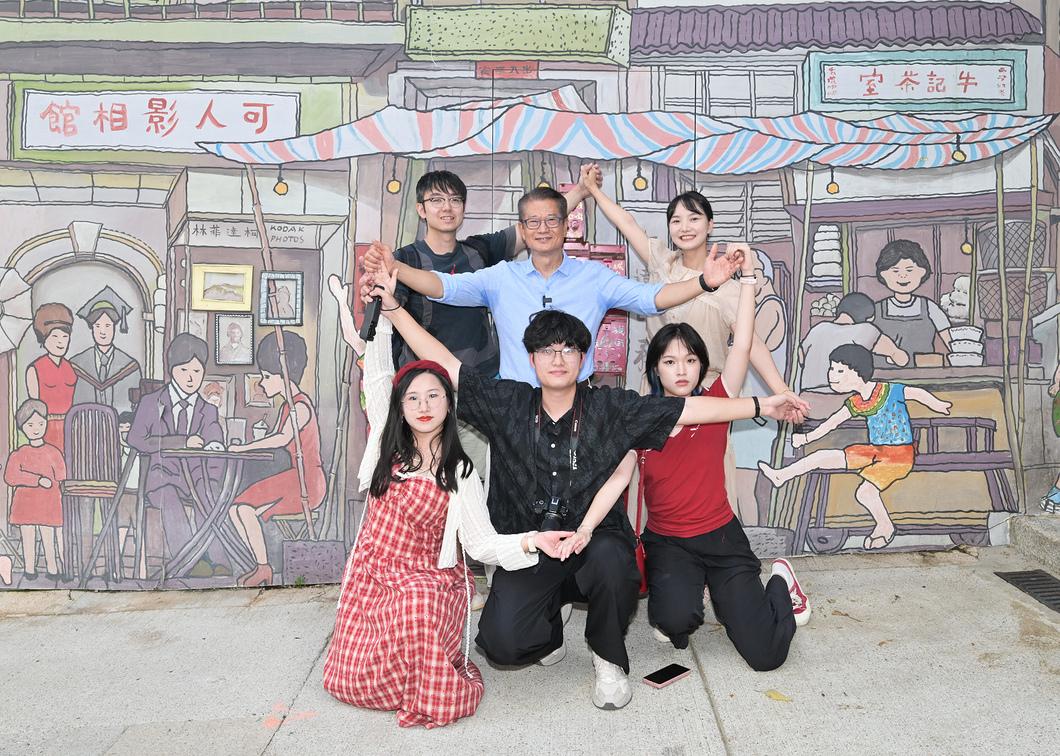 陳茂波(中)與遊客在壁畫前打卡留念。（財政司司長網誌）