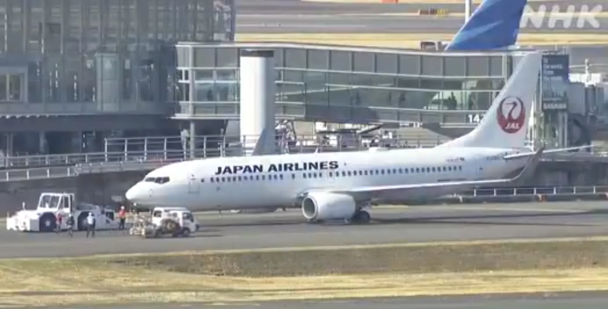 日本航空一架客機在東京羽田機場跑道滑行時爆胎，機上約60名乘客沒有受傷。工程人員即場更換漏氣輪胎，之後將客機移至停機坪並讓乘客下機。(電視畫面)